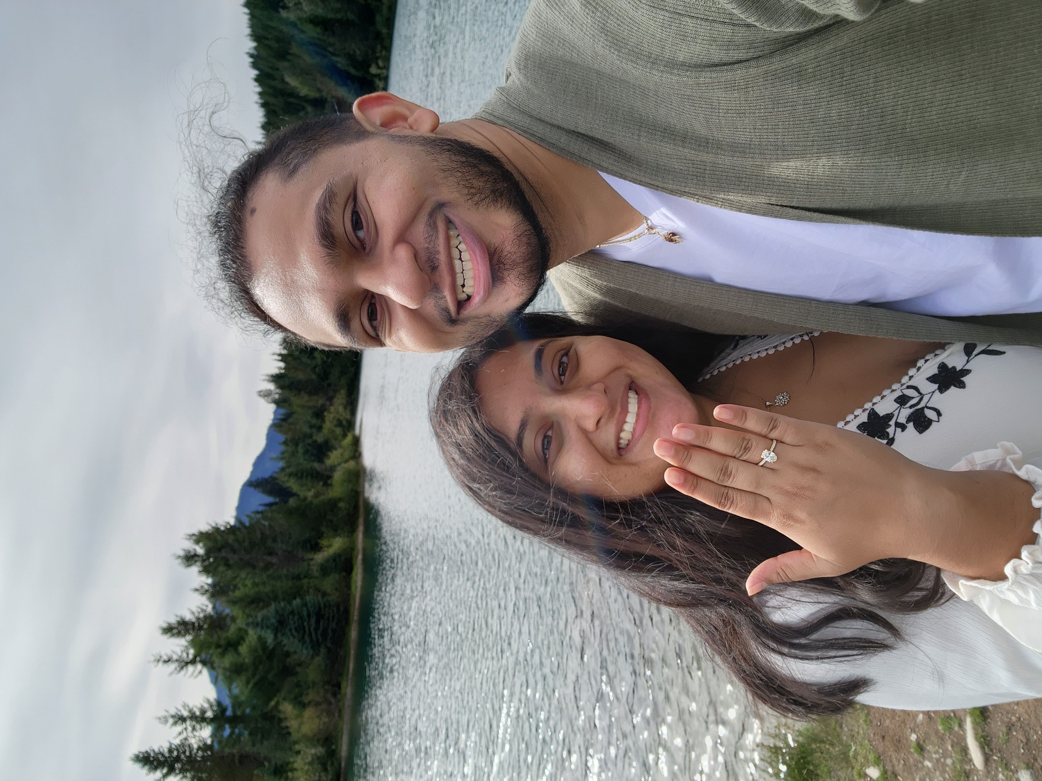 A couple posing for a picture and lady wearing ring in his hand
