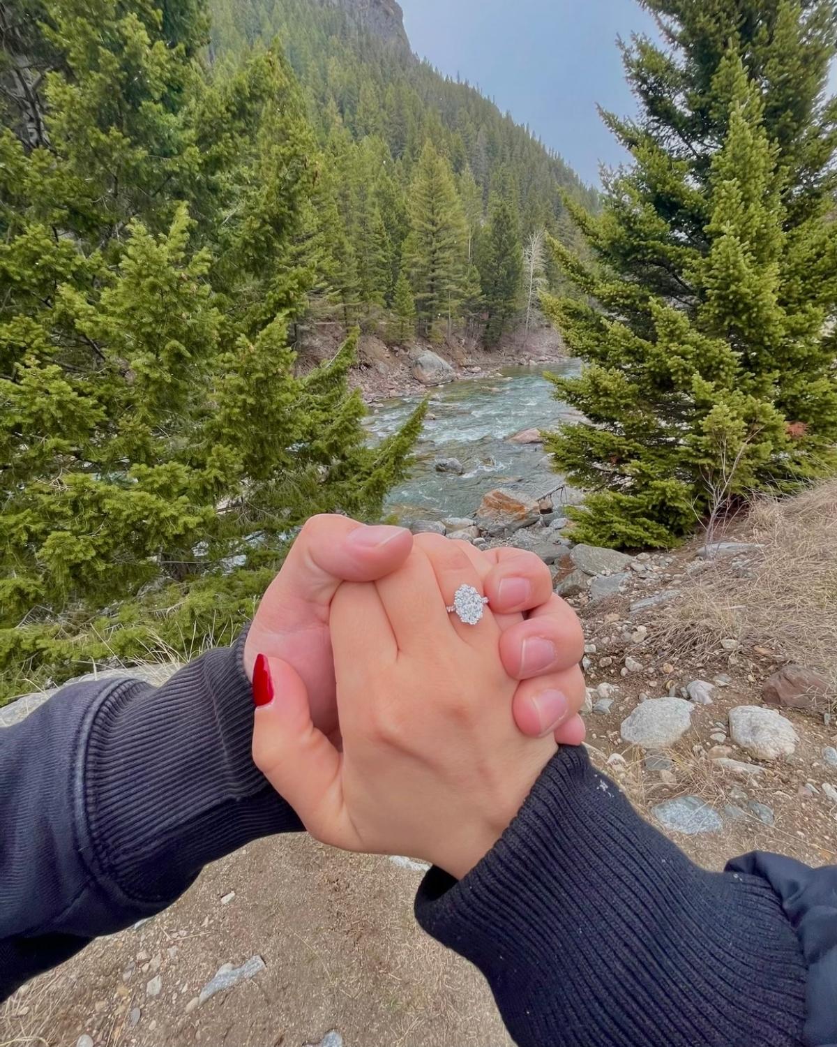 A couple hand's with a ring on it by a river