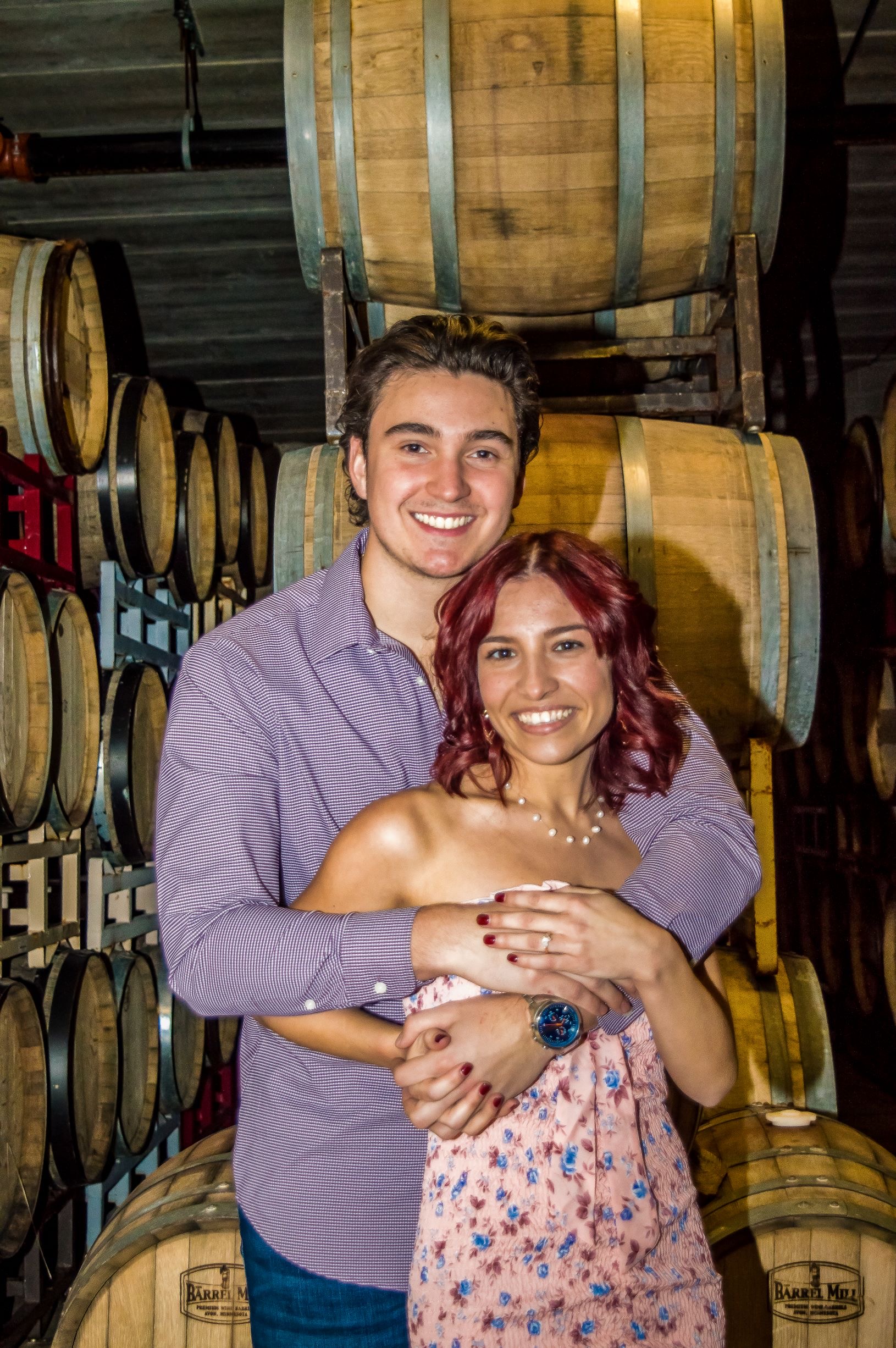 A couple posing in front of a stack of barrels