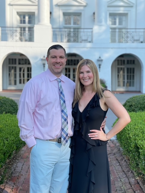 A couple posing for a picture in front of a white building