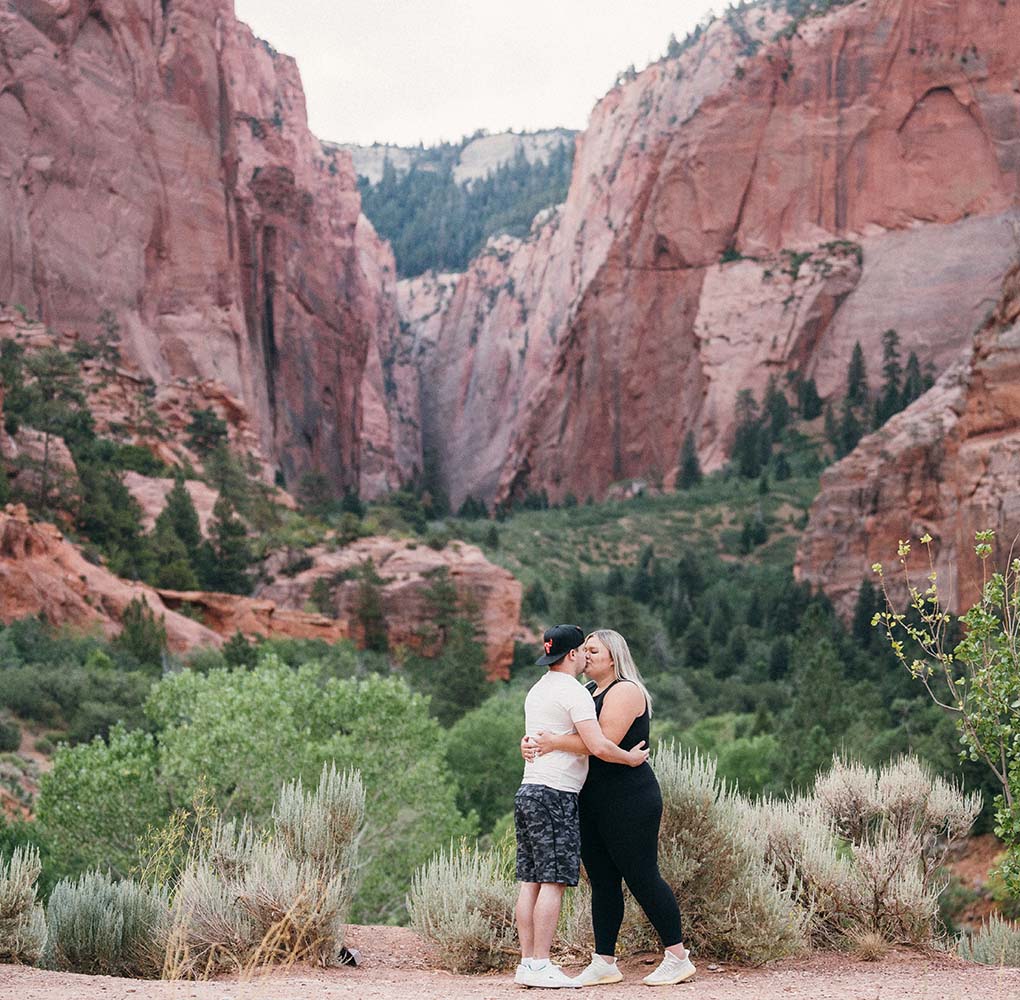 couple kissing in front of a canyon